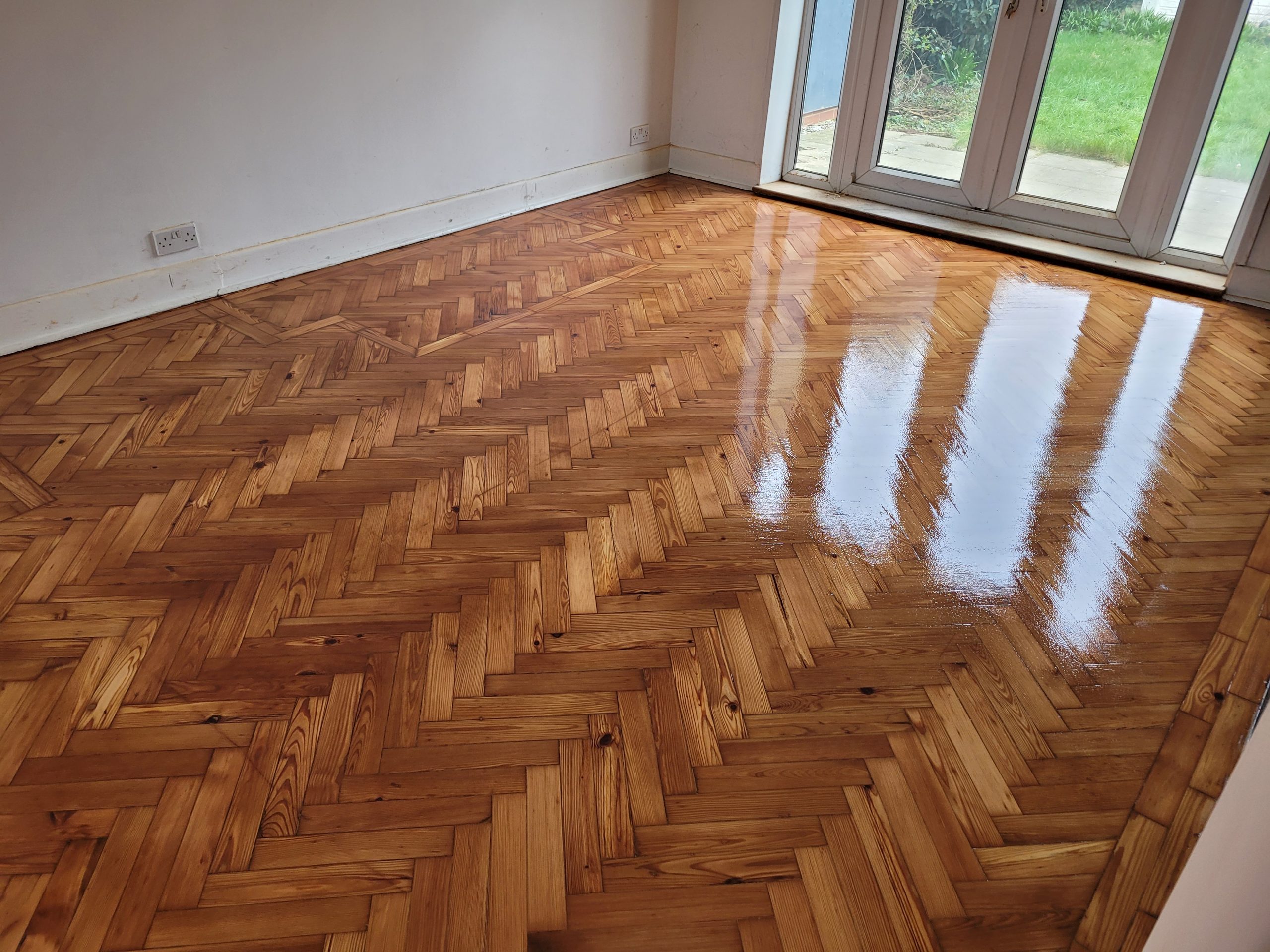 Gleaming herringbone parquet floor in a Greenwich living room after professional wood floor sanding and high-gloss lacquer finishing.