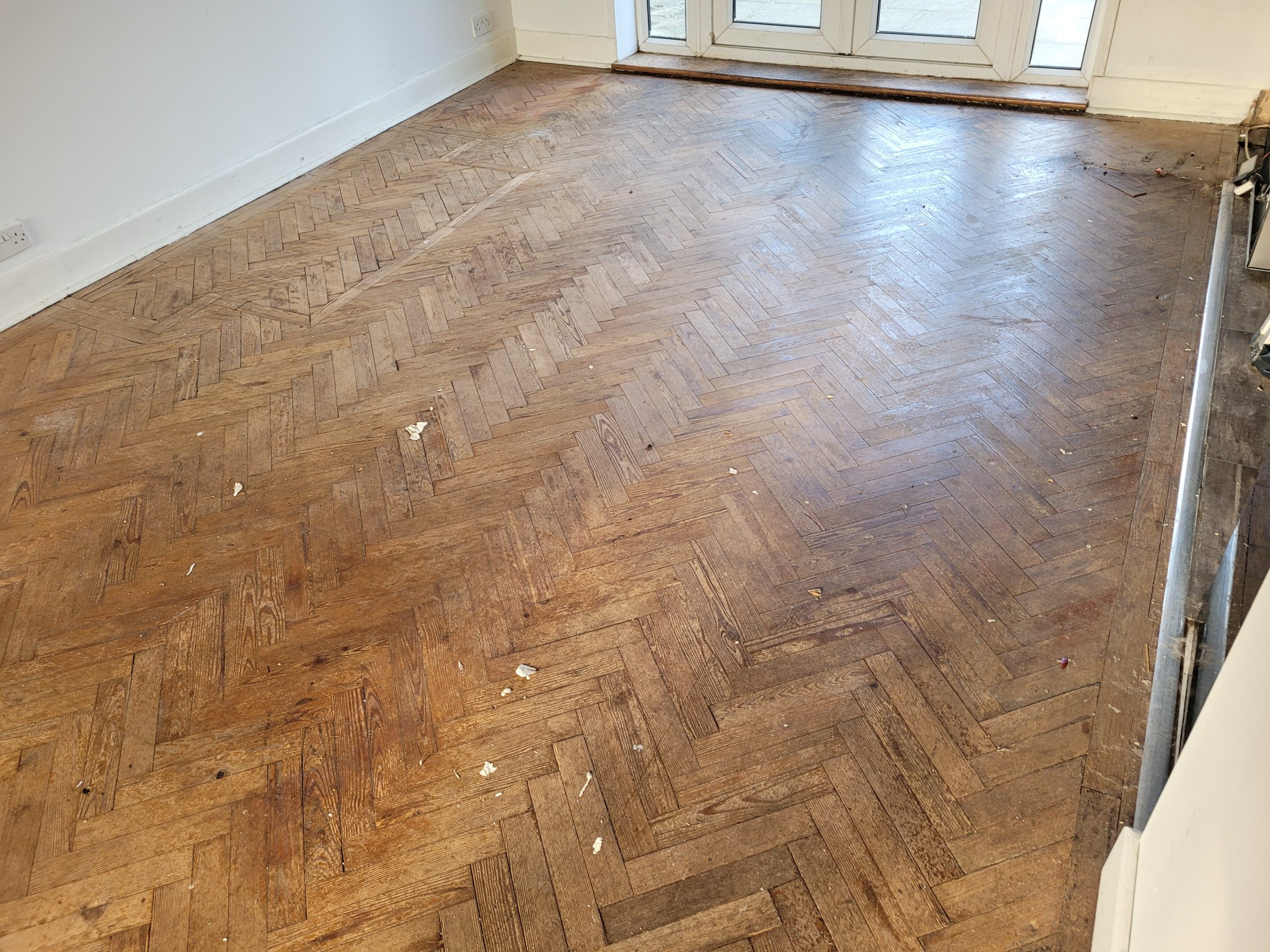 Worn herringbone parquet floor in a Greenwich living room before professional wood floor sanding and restoration.