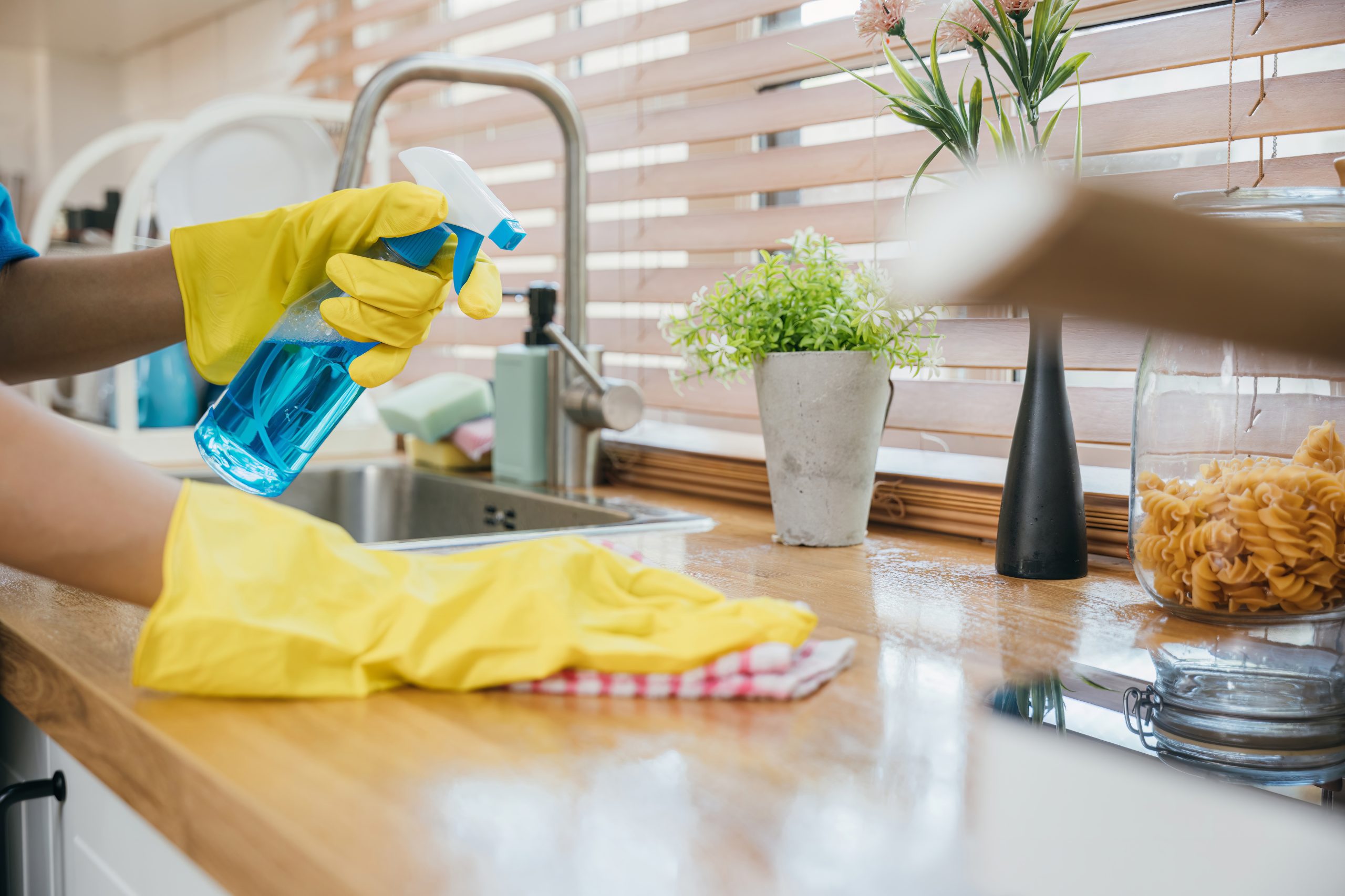 Kitchen Worktop Sanding in Greenwich – aftercare cleaning of an oiled oak butcher-block worktop with spray bottle and yellow gloves; oak hardwood kitchen floor.