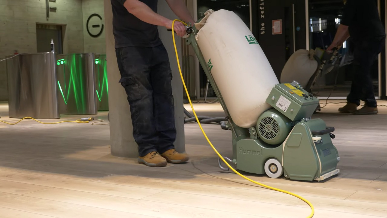 Wood Floor Sanding in Greenwich on a light oak hardwood commercial lobby floor, with a technician operating a Hummel sanding machine.