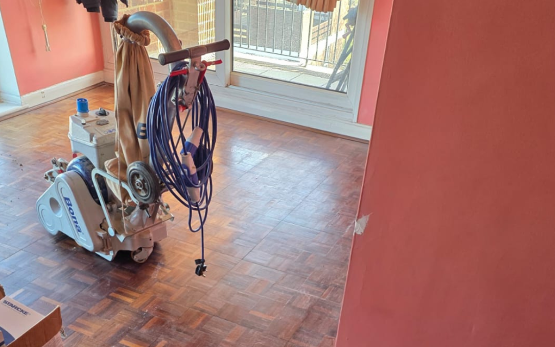 Wood Floor Sanding in Greenwich on an oak mosaic parquet floor using a professional Bona sanding machine in a bright living room.