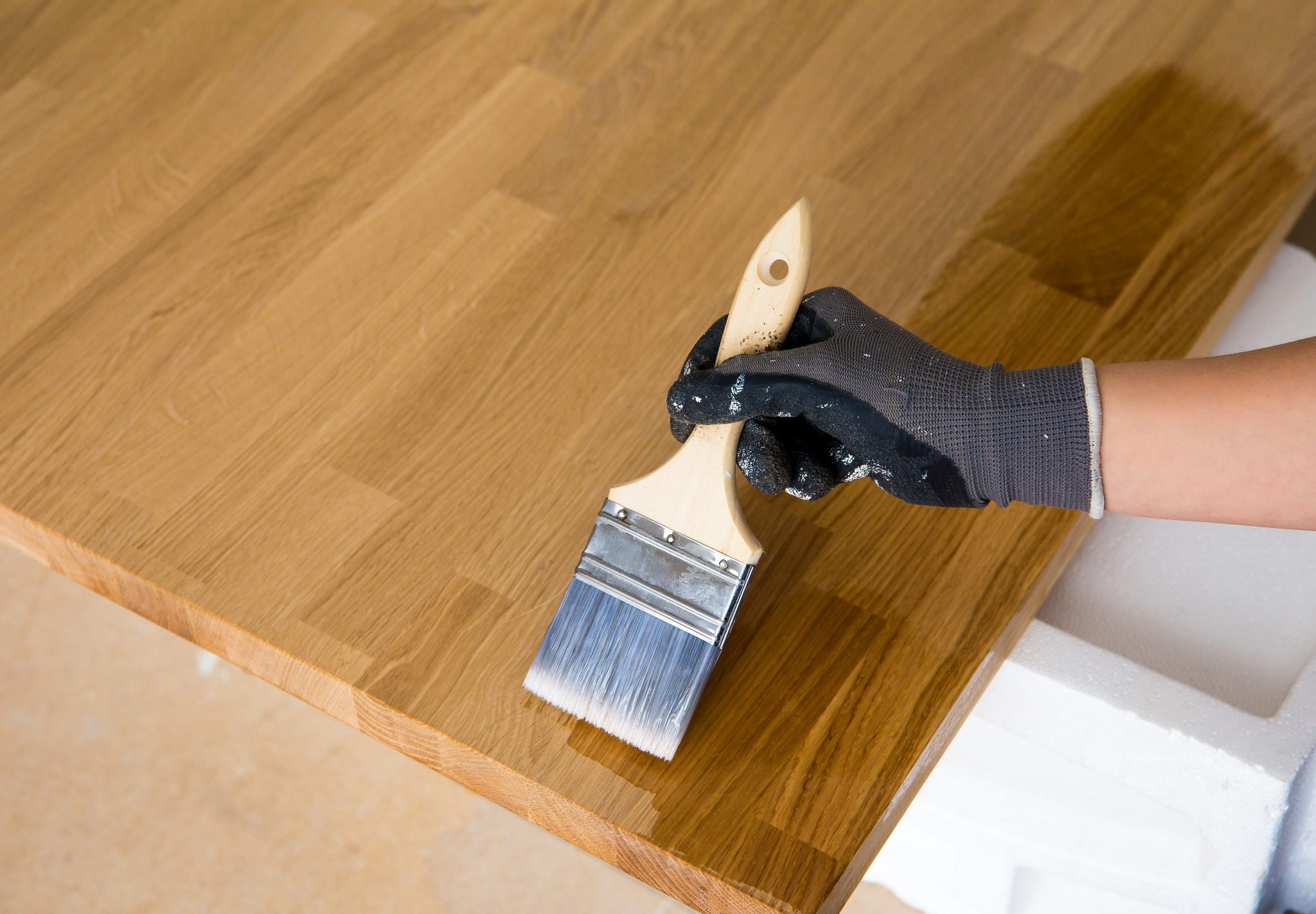 Worktop Refinishing in Greenwich on a solid oak hardwood kitchen worktop, with a professional applying clear protective finish for a smooth, hygienic surface.