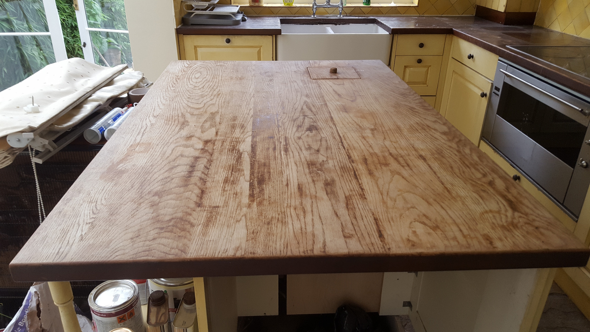 Worktop Refinishing in Greenwich on a worn solid oak hardwood island worktop with adjoining oak plank wood floor, ready for sanding and restoration.